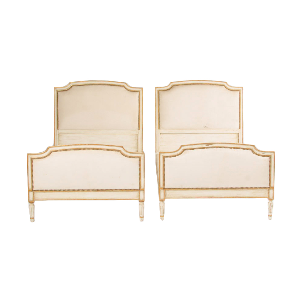 A pair of Louis XVI style painted twin beds with nail head upholstered headboard and footboard circa 1940.